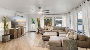 Ein geräumiges Wohnzimmer mit einer großen Eckcouch, einem Flachbildfernseher und einem Deckenventilator.