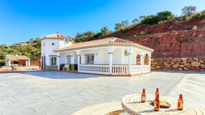 Un edificio blanco con techo de tejas, piscina y pared de piedra.