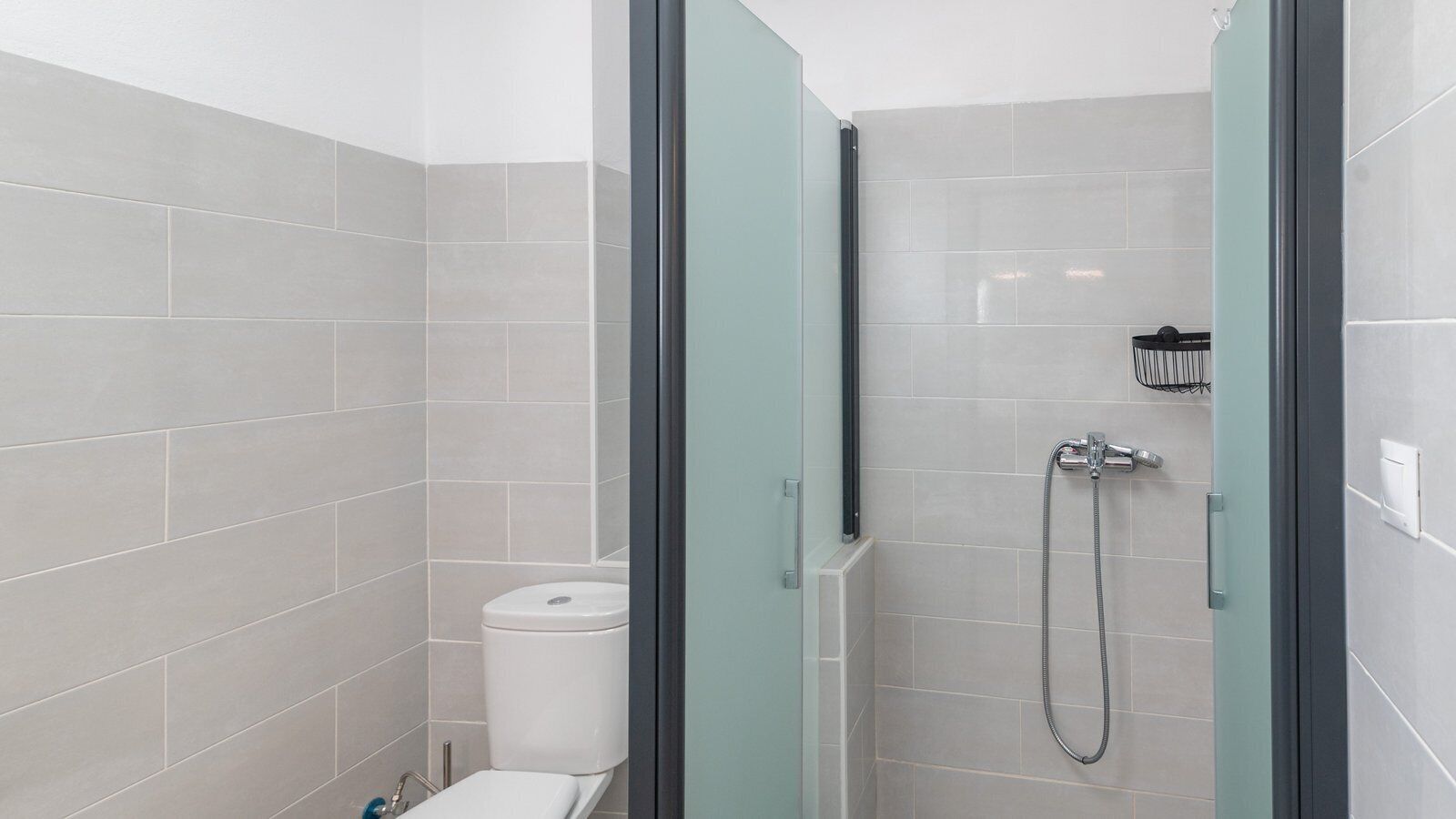 Un baño moderno con cabina de ducha de vidrio, inodoro y secador de manos.
