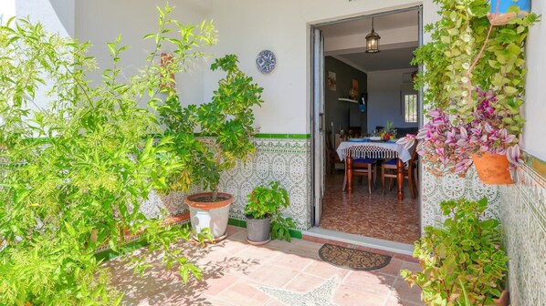 A patio with potted plants, a tiled floor, and a dining table with chairs. - Casa Pozo Antequera by Ruralidays (Málaga)