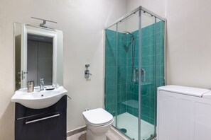 A bathroom with a white sink, a toilet, a glass shower enclosure, and a white radiator. - PANIZZA 8 · Grazioso monolocale, posizione elegante e centrale (Milano)
