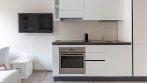 Une cuisine moderne équipée d’un four encastré, d’un évier et d’un téléviseur à écran plat fixé au mur.