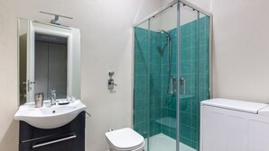 Une salle de bain avec un lavabo blanc, des toilettes, une douche en verre et un radiateur blanc.