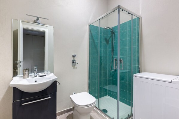 Une salle de bain avec un lavabo blanc, des toilettes, une douche en verre et un radiateur blanc.