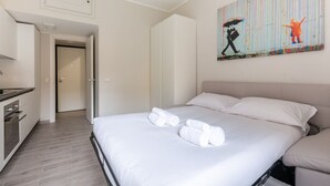 Una camera d'albergo con un letto, un quadro appeso al muro e un angolo cottura.