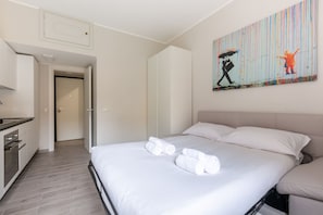 Una habitación de hotel con una cama, un cuadro en la pared y una zona de cocina.