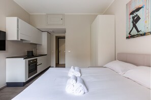 A modern hotel room with a bed, a kitchen area, and a painting on the wall. - PANIZZA 8 · Grazioso monolocale, posizione elegante e centrale (Milano)