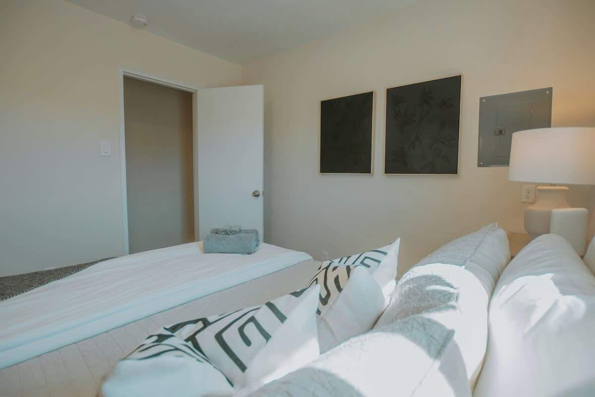 A hotel room with a bed, a sofa, and two wall-mounted picture frames.