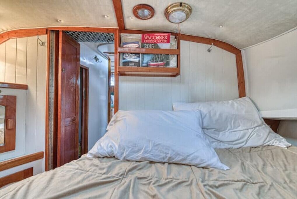 L’intérieur chaleureux d’un chalet avec un lit, une étagère sur laquelle repose un livre intitulé « Guide de navigation Waggoner 2015 », et une porte en bois.