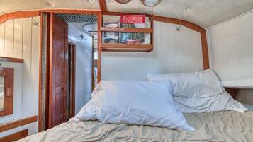 L’intérieur chaleureux d’un chalet avec un lit, une étagère sur laquelle repose un livre intitulé « Guide de navigation Waggoner 2015 », et une porte en bois.