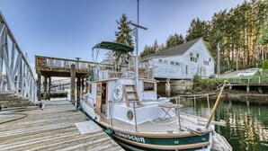 A boat docked at a wooden pier with a house in the background. - Historic Charming Boat in Downtown Harbor

 (Gig Harbor)