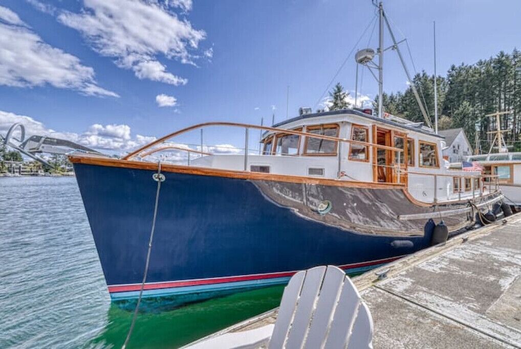 Uma grande embarcação azul atracada em um cais, com cabine e pequena área de convés.