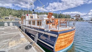 A wooden boat docked at a pier with a view of a forested shoreline. - Spacious 46' Yacht: Luxury, kayaks, walk to town

 (Gig Harbor)