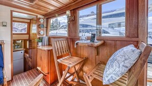 A compact kitchen with wooden cabinetry, a small refrigerator, and a window overlooking a snowy landscape. - Spacious 46' Yacht: Luxury, kayaks, walk to town

 (Gig Harbor)