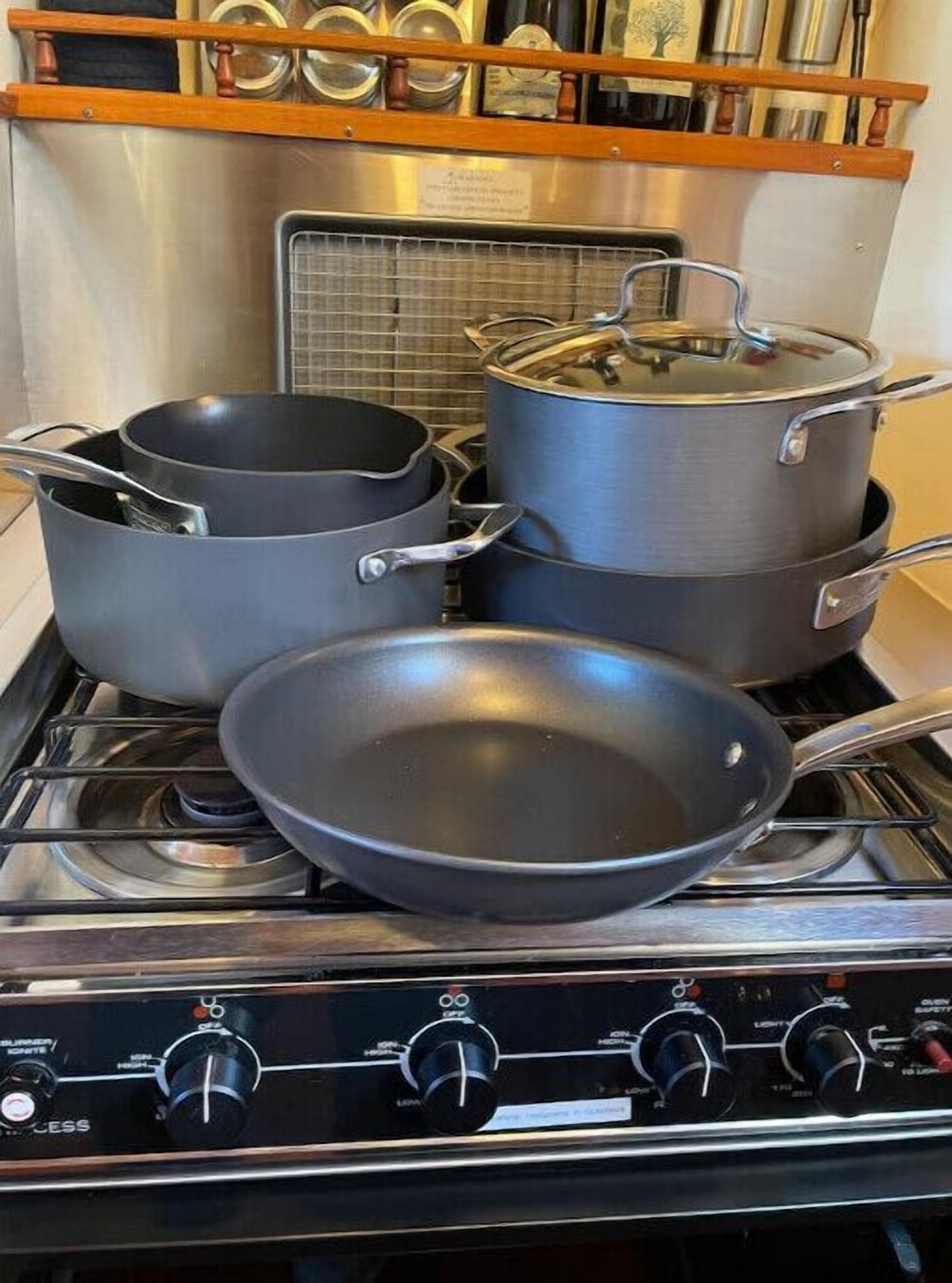 A kitchen with a stove, pots, pans, and a frying pan.