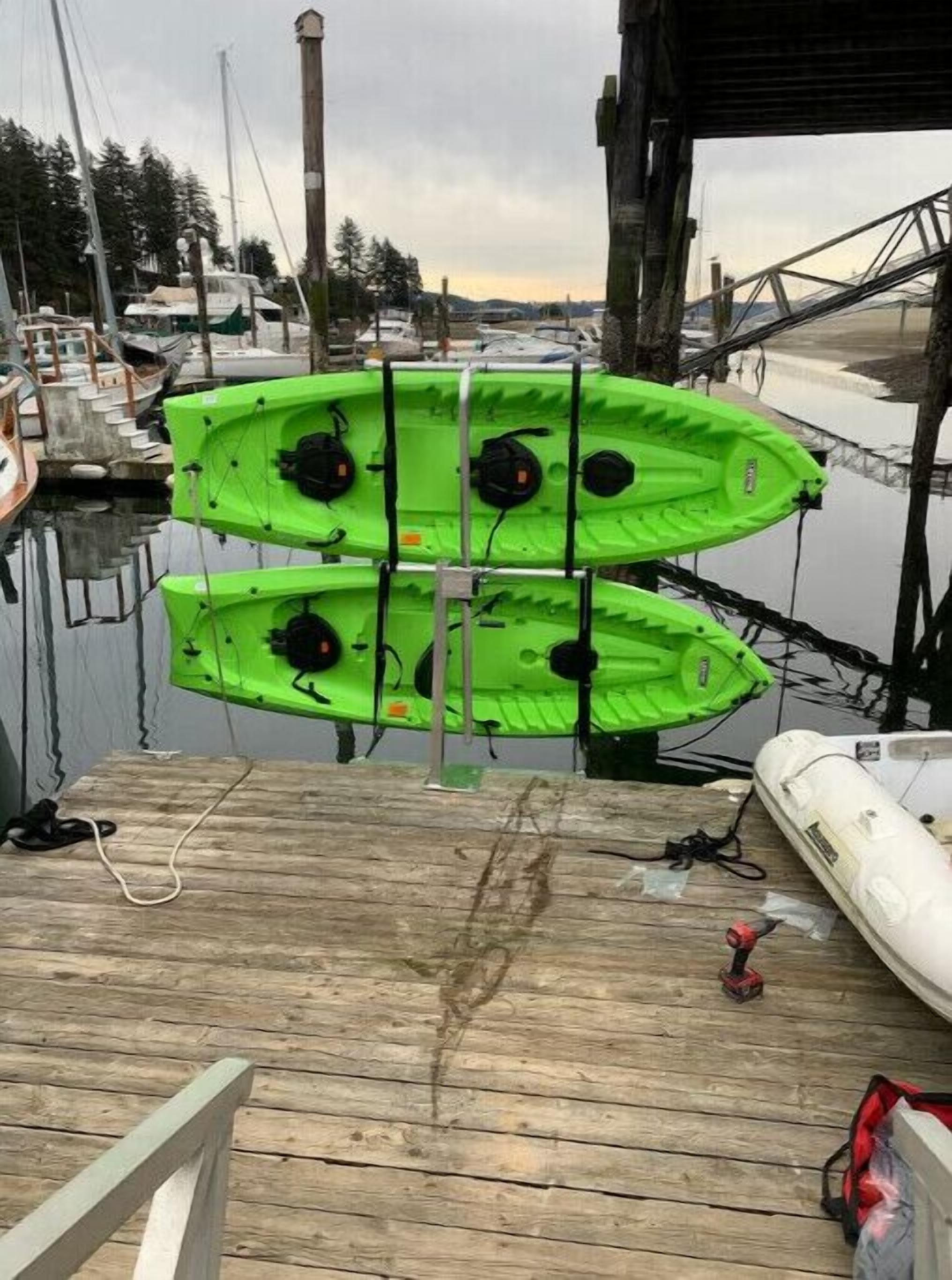 A wooden dock with two green kayaks secured on a rack.