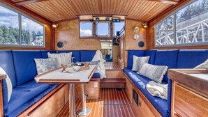 Un interior acogedor con paneles de madera, asientos tapizados en azul y una mesa central.