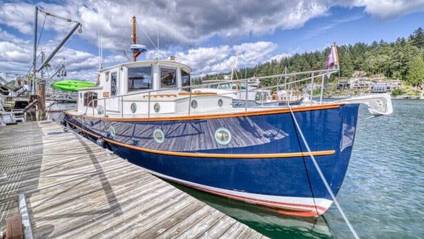 Un barco azul amarrado a un muelle de madera, con un bosque al fondo.