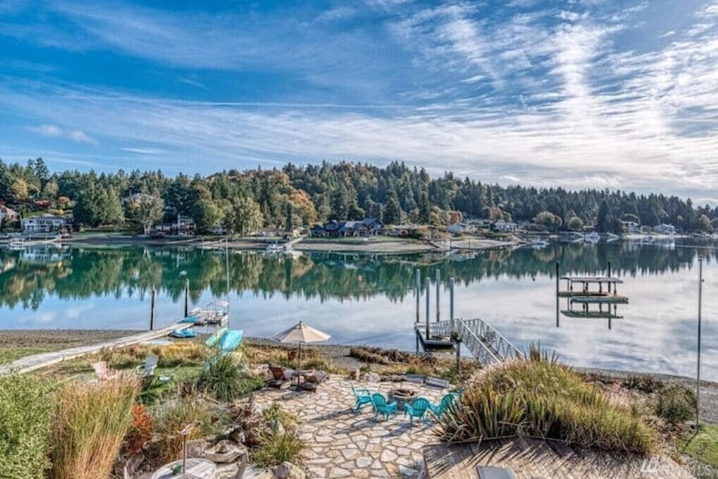 Une terrasse au bord du lac, avec un sol en pierre, des sièges d’extérieur et une jetée qui s’avance dans l’eau.