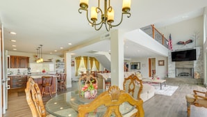 A spacious living area with a glass dining table, wooden chairs, and a chandelier. - Group-Friendly Desert Escape! Putting Green, Pool (Phoenix)