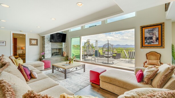 A spacious living room with a large window, a fireplace, and a view of the outdoors. - Group-Friendly Desert Escape! Putting Green, Pool (Phoenix)