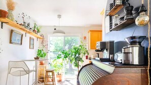 Une cuisine avec un plan de travail en bois, une ampoule suspendue et une fenêtre donnant sur un paysage verdoyant.
