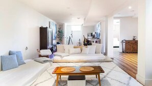 Un salon spacieux avec un grand canapé, une table basse et une vue sur la cuisine.