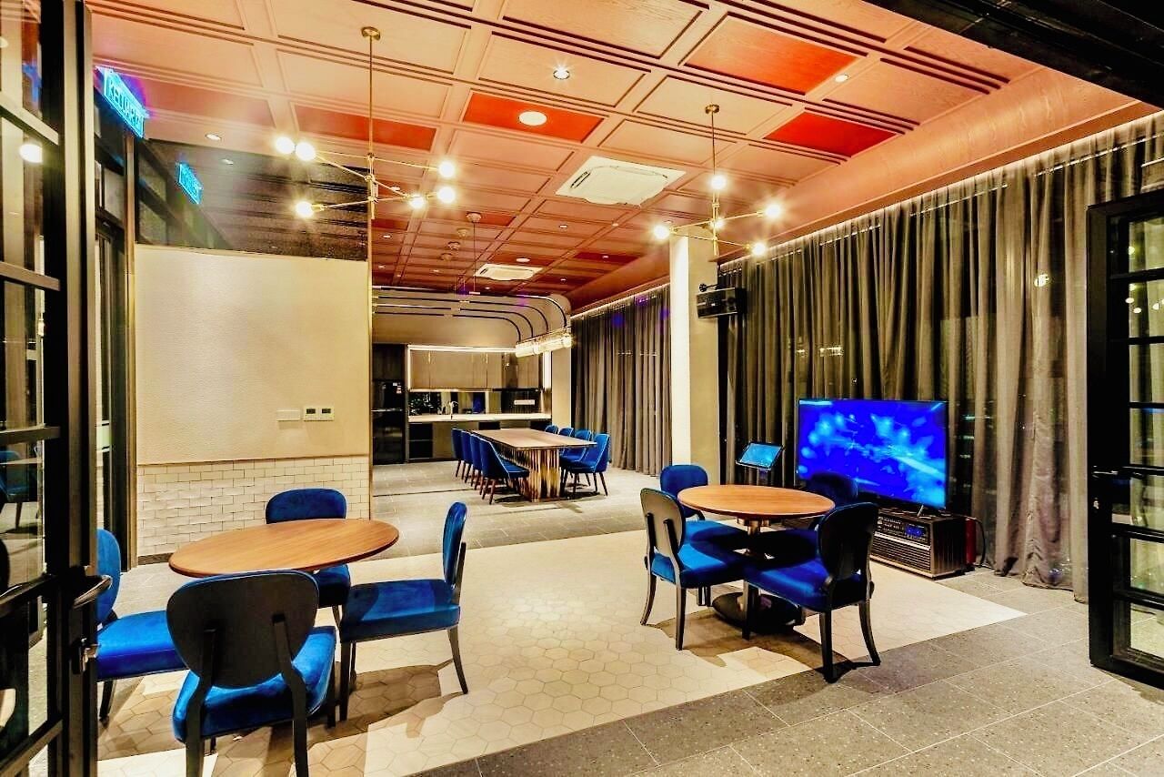 Een moderne hotellobby met zithoeken, een televisie en een keuken op de achtergrond.