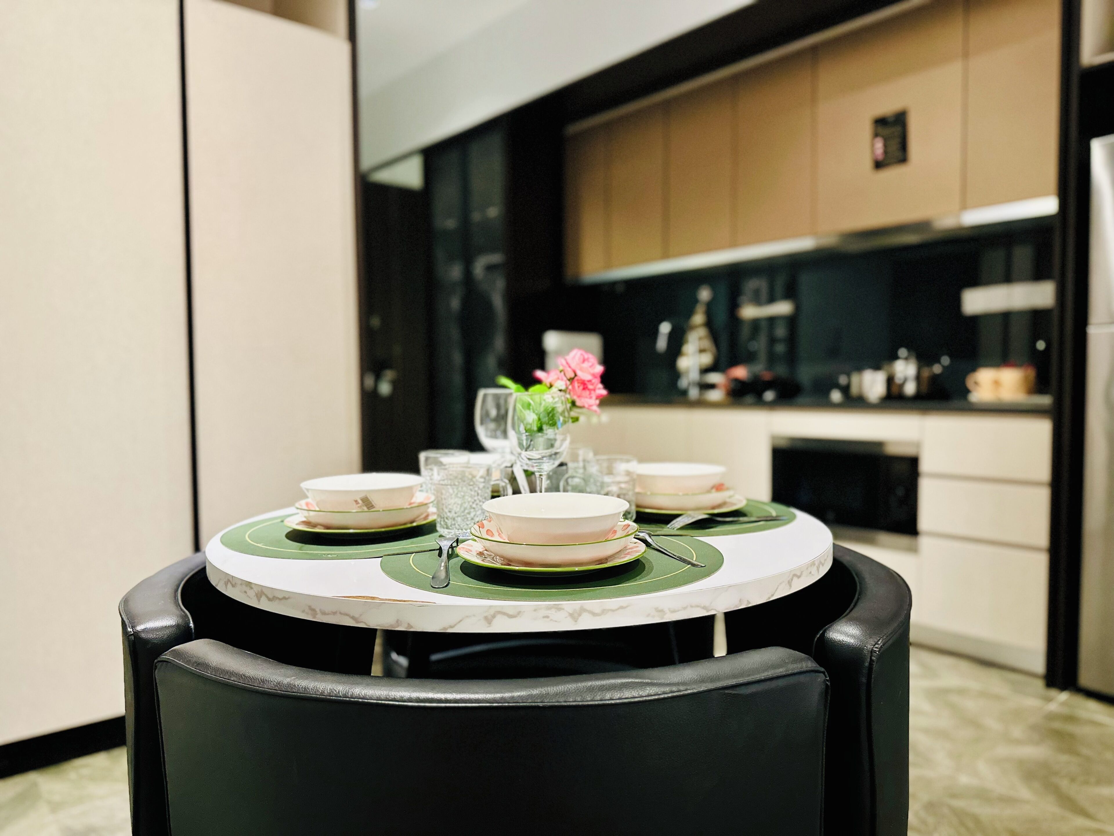 A dining table set with plates, glasses, and a vase with flowers.