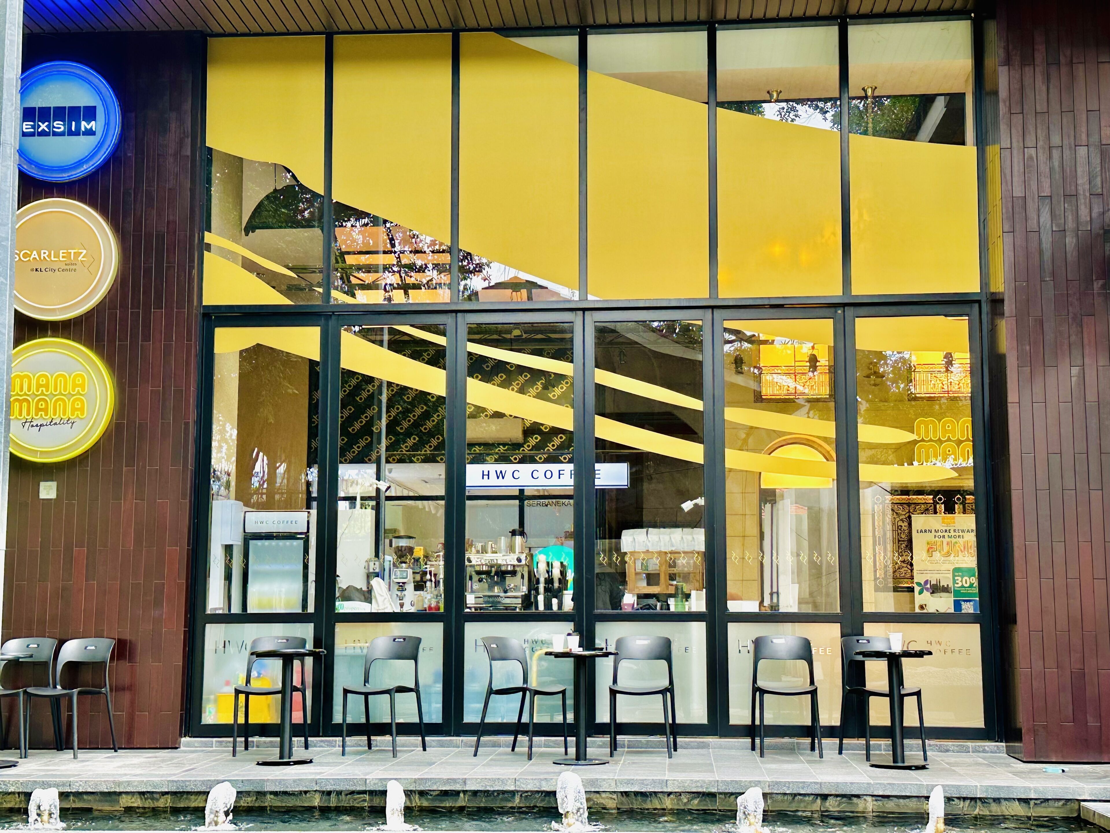 Un café à la façade jaune, doté de grandes fenêtres et d’une terrasse.