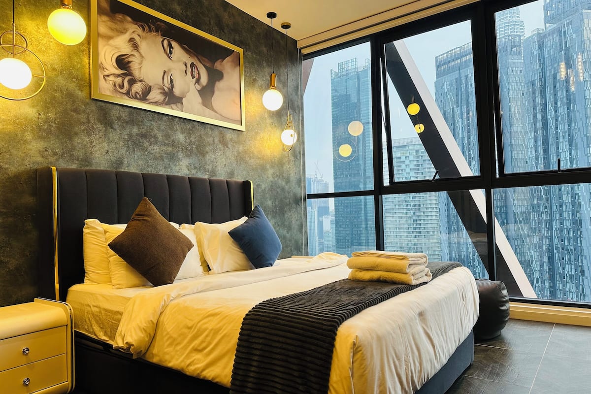 Een moderne slaapkamer met een groot bed, een nachtkastje en een raam met uitzicht op de stad.