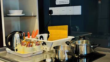 A kitchen with a stove, pots, a coffee maker, and a sign indicating a power switch for kitchen appliances.