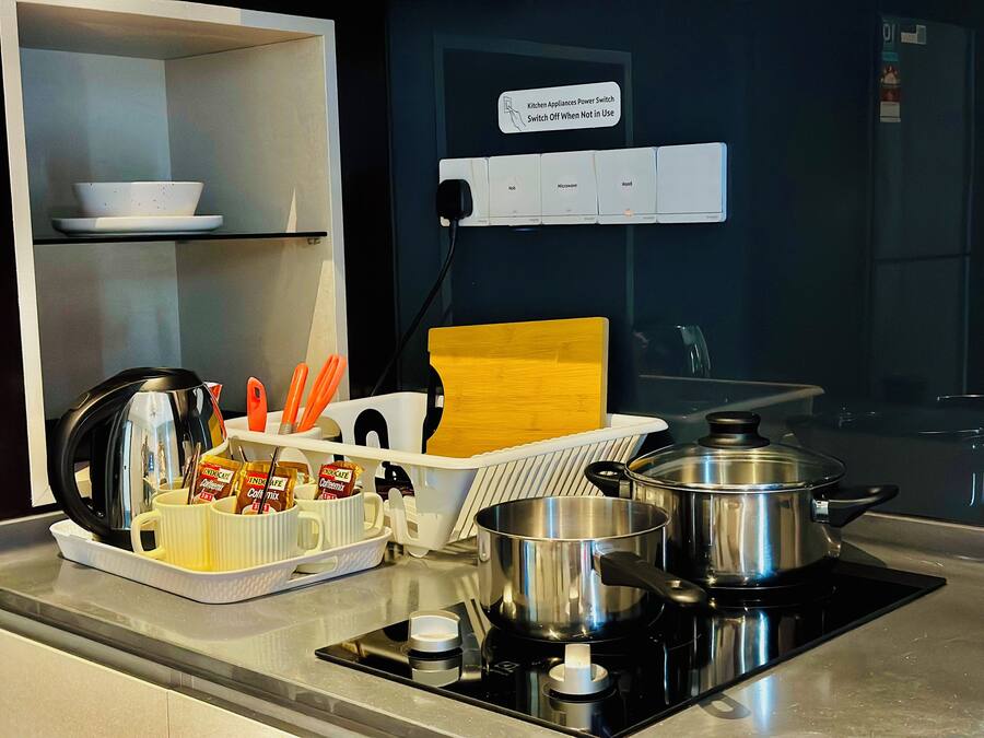 A kitchen with a stove, pots, a coffee maker, and a sign indicating a power switch for kitchen appliances.