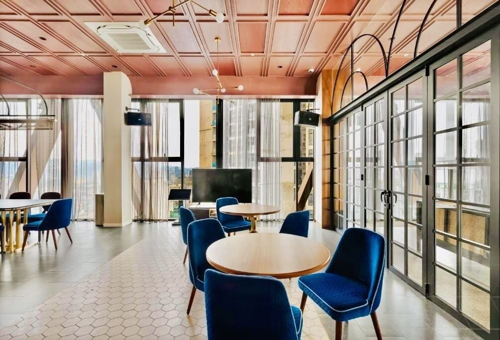 A modern conference room with hexagonal patterned flooring, round tables, and blue chairs.