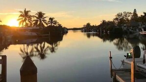 Une rivière paisible au coucher du soleil, avec un quai et des bateaux.
