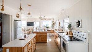 A spacious kitchen with wooden cabinets, a central island, and modern appliances. - Charming Bungalow on the Bay (East Hampton)
