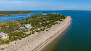 A coastal property with a sandy beach, a small cluster of houses, and a large body of water. - Charming Bungalow on the Bay (East Hampton)