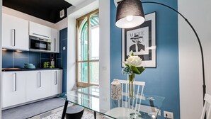 A modern kitchen with white cabinets, a glass dining table, and a blue accent wall. - BDC - Rome with a view! (Roma)
