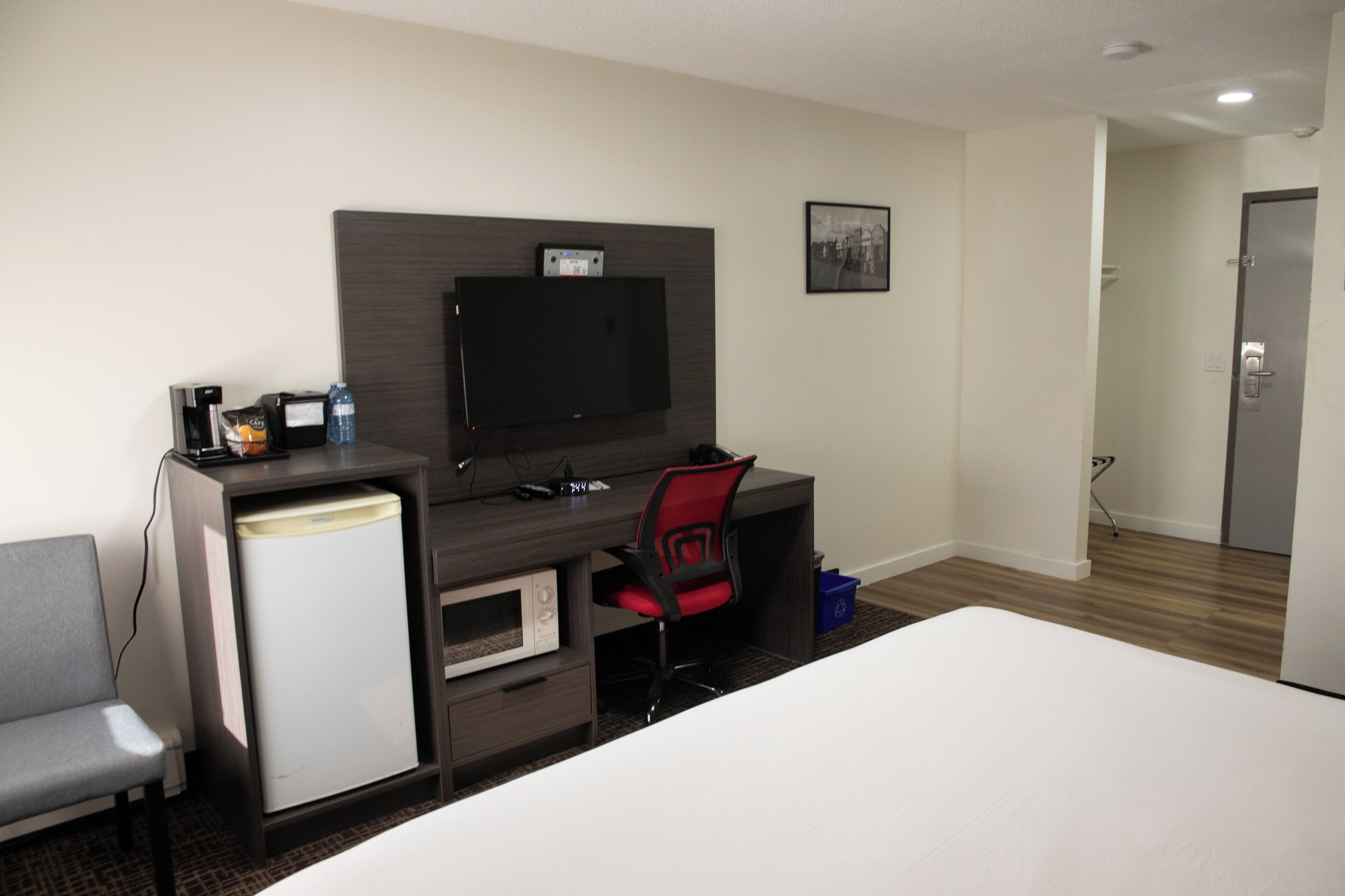 A hotel room with a bed, a desk with a computer, a television, and a microwave.