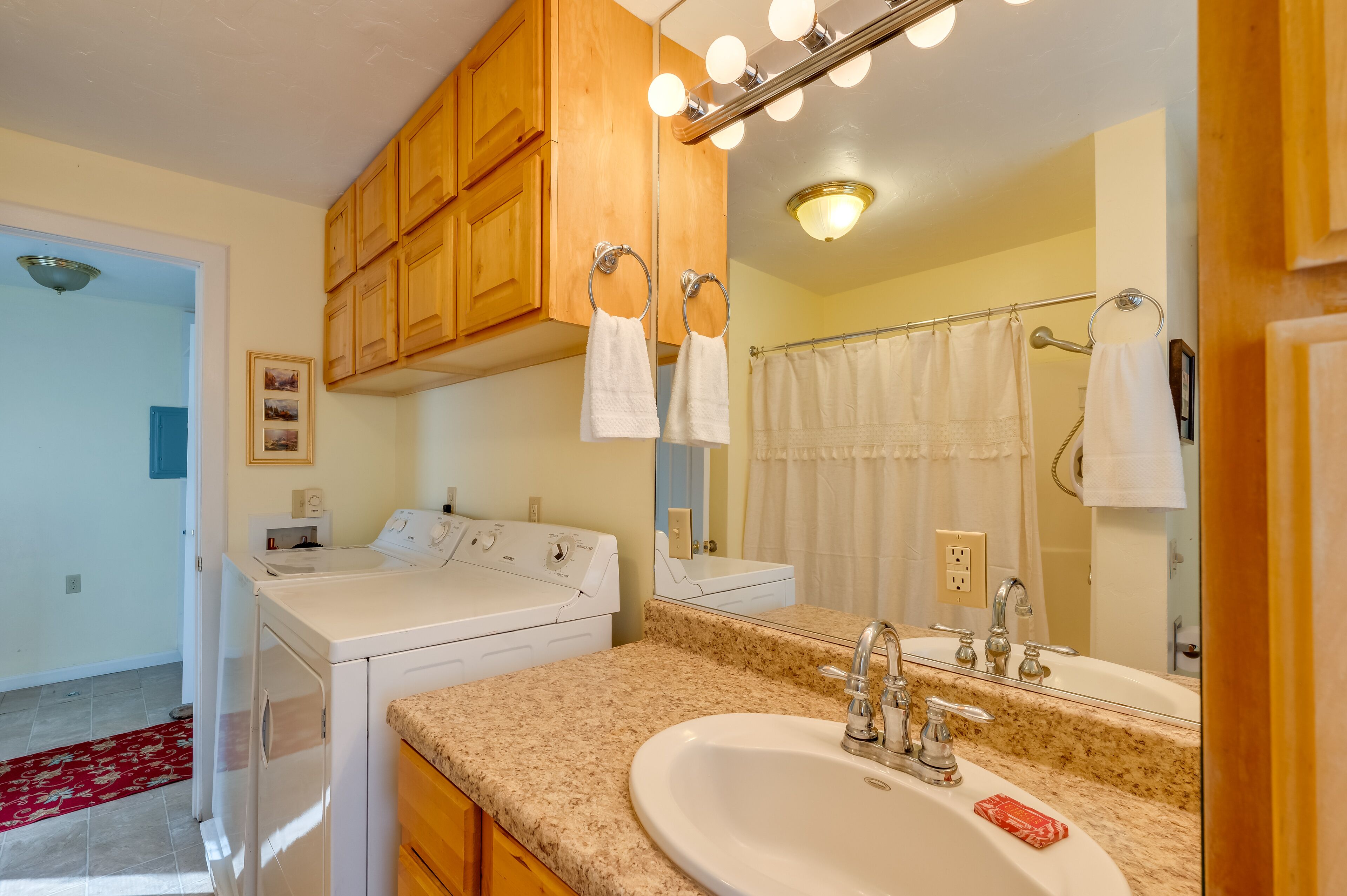 Un baño con muebles de madera, un lavamanos, un espejo y una zona de ducha.