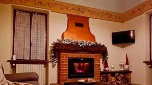 Un salon chaleureux avec une cheminée, un téléviseur fixé au mur et un coin salon confortable.