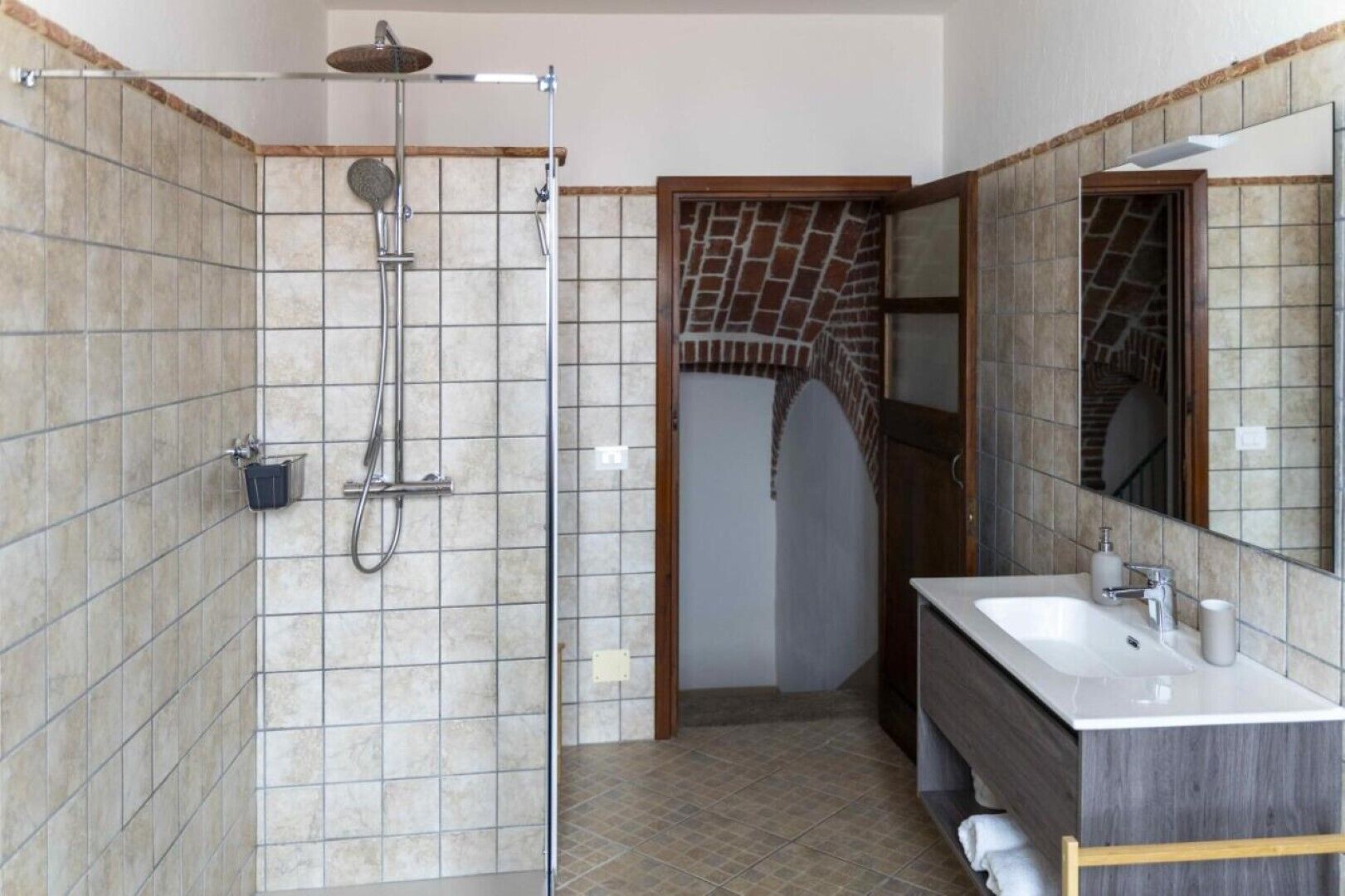 A bathroom with a shower, a sink, and a mirror.