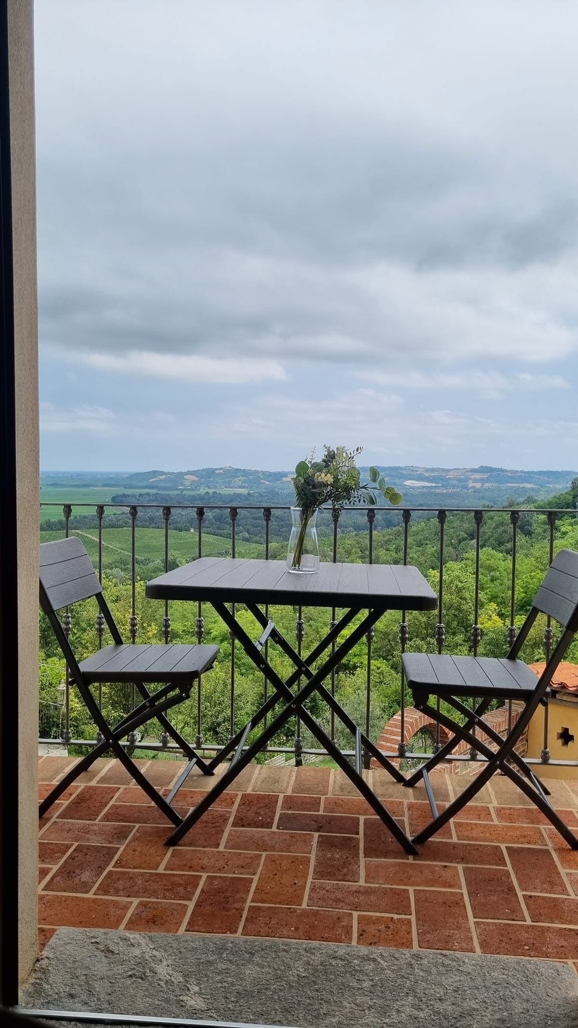 A balcony with a table and two chairs, overlooking a scenic landscape.
