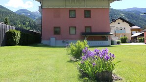 A two-story building with a balcony, surrounded by a well-maintained lawn and purple flowers. - Haus Elena (Rangersdorf)