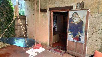 Una habitación rústica con una puerta de madera, una silla colgante, un cartel y una pequeña mesa.
