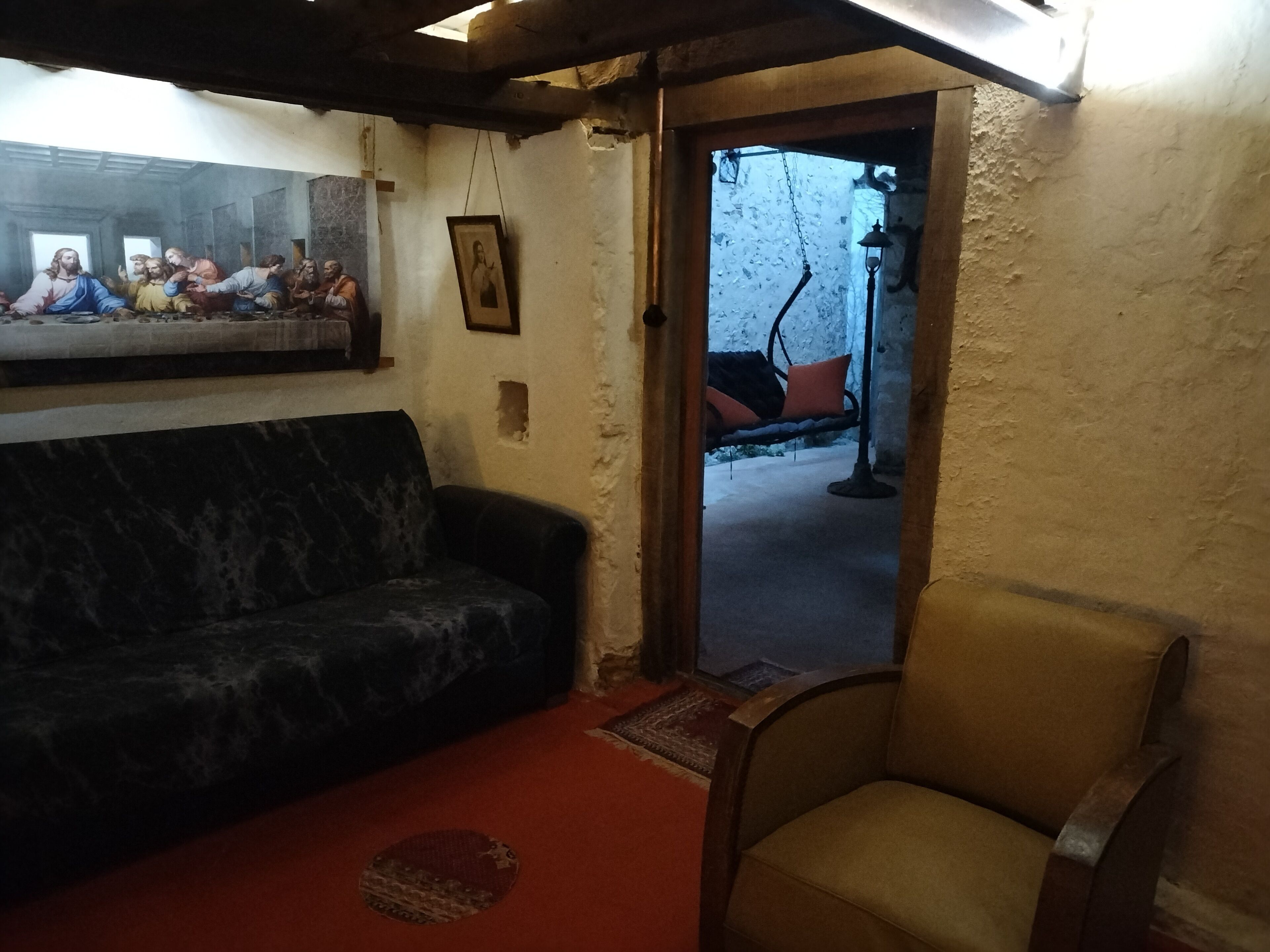 Un salon avec un canapé à motifs sombres, un fauteuil beige, une œuvre d’art encadrée au-dessus du canapé et un luminaire suspendu.