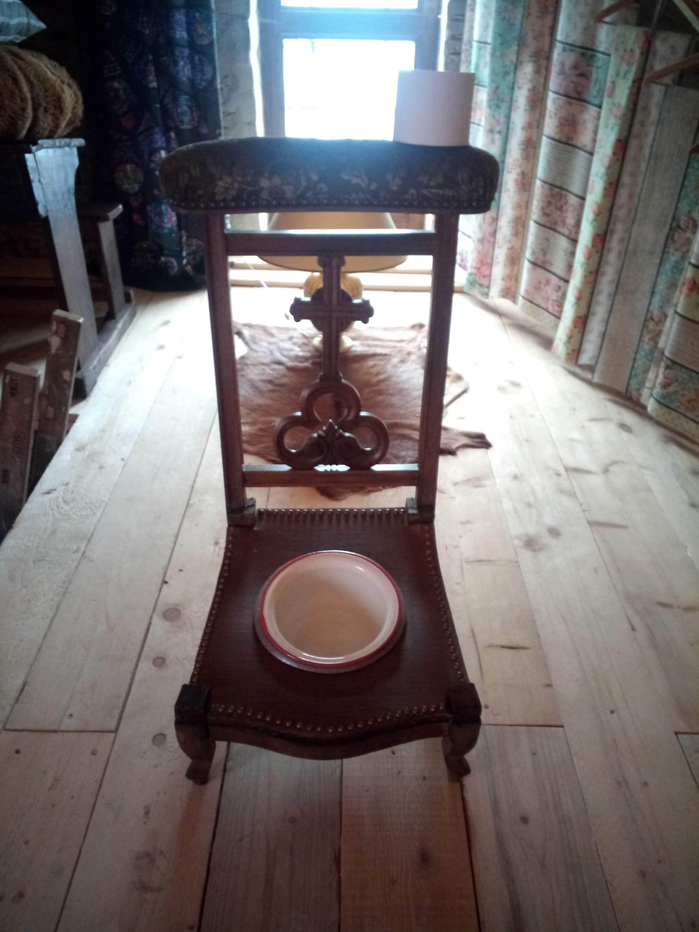 Una mesa de madera con una superficie decorativa y un cuenco encima, sobre un piso de madera en una habitación con cortinas estampadas y una ventana al fondo.