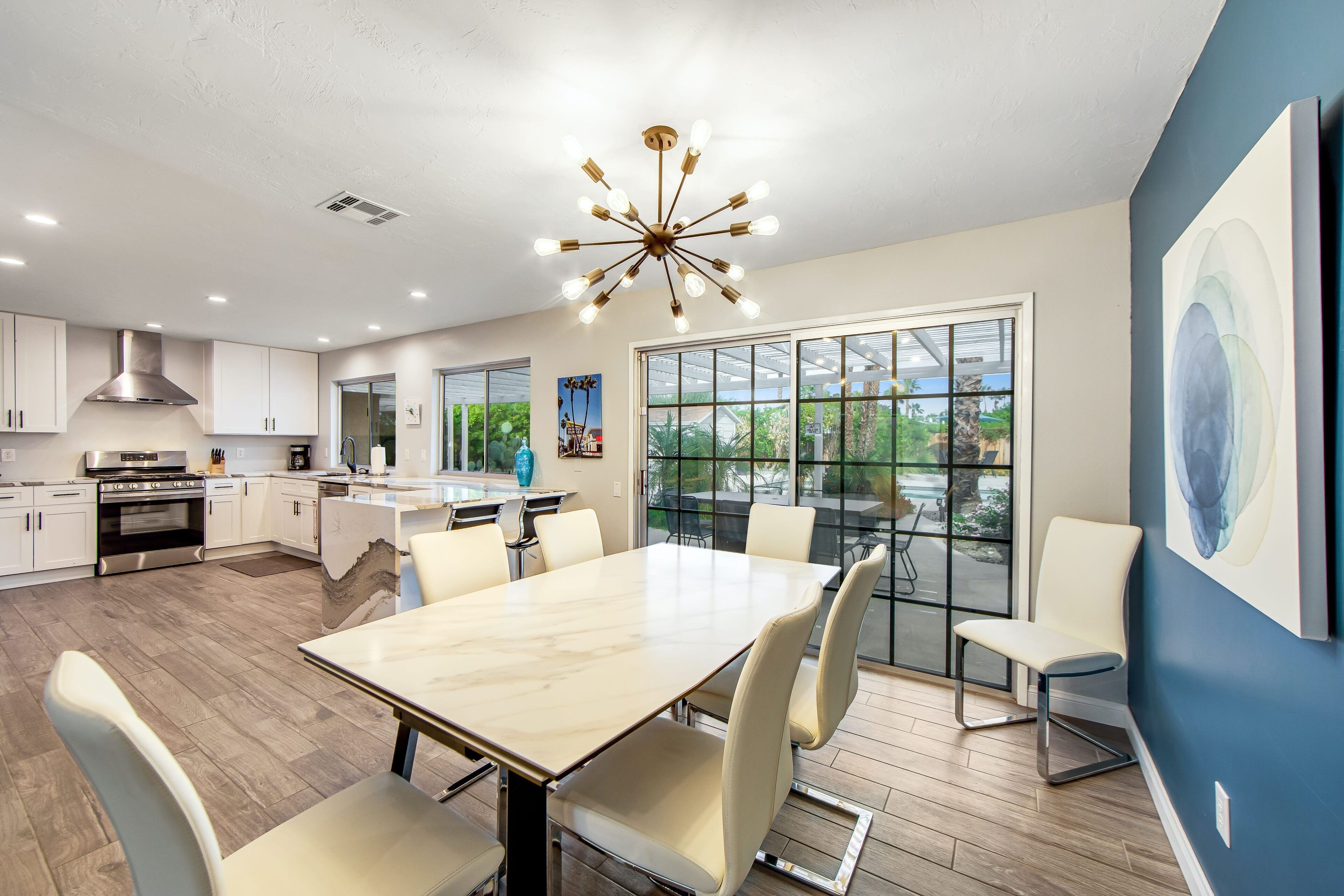 A modern kitchen with white cabinets, a stainless steel range hood, and a large island with seating.