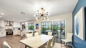 A modern kitchen with white cabinets, a stainless steel range hood, and a large island with seating. - Upscale private paradise on large dog-friendly lot w/ free EV charger (Palm Springs)