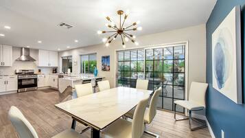 A modern kitchen with white cabinets, a stainless steel range hood, and a large island with seating.